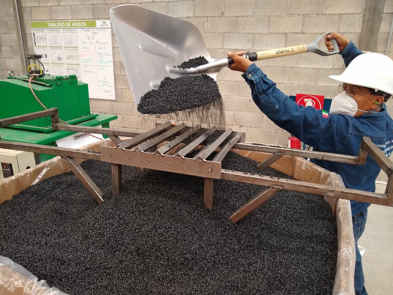 Operador cribando pellet reciclado sobre malla